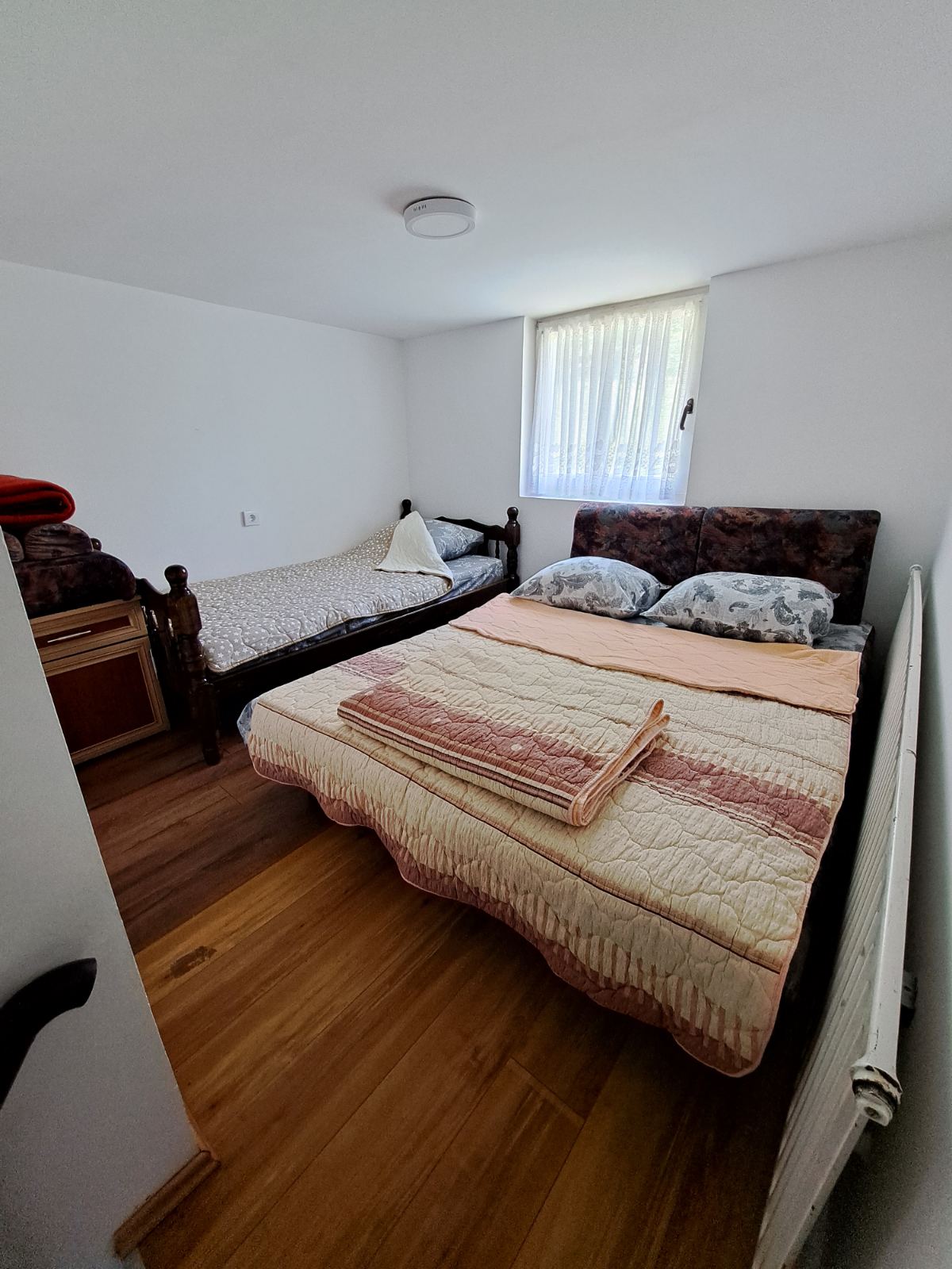 Đokić Apartman3 Spavaća soba na spratu sa dva ležaja, ormarić za odlaganje i prozor sa pogledom na prirodu
